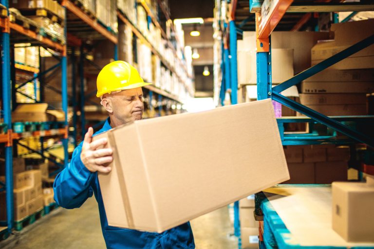 Warehouse,Worker,Lifting,Heavy,Box,On,Storage,Shelf